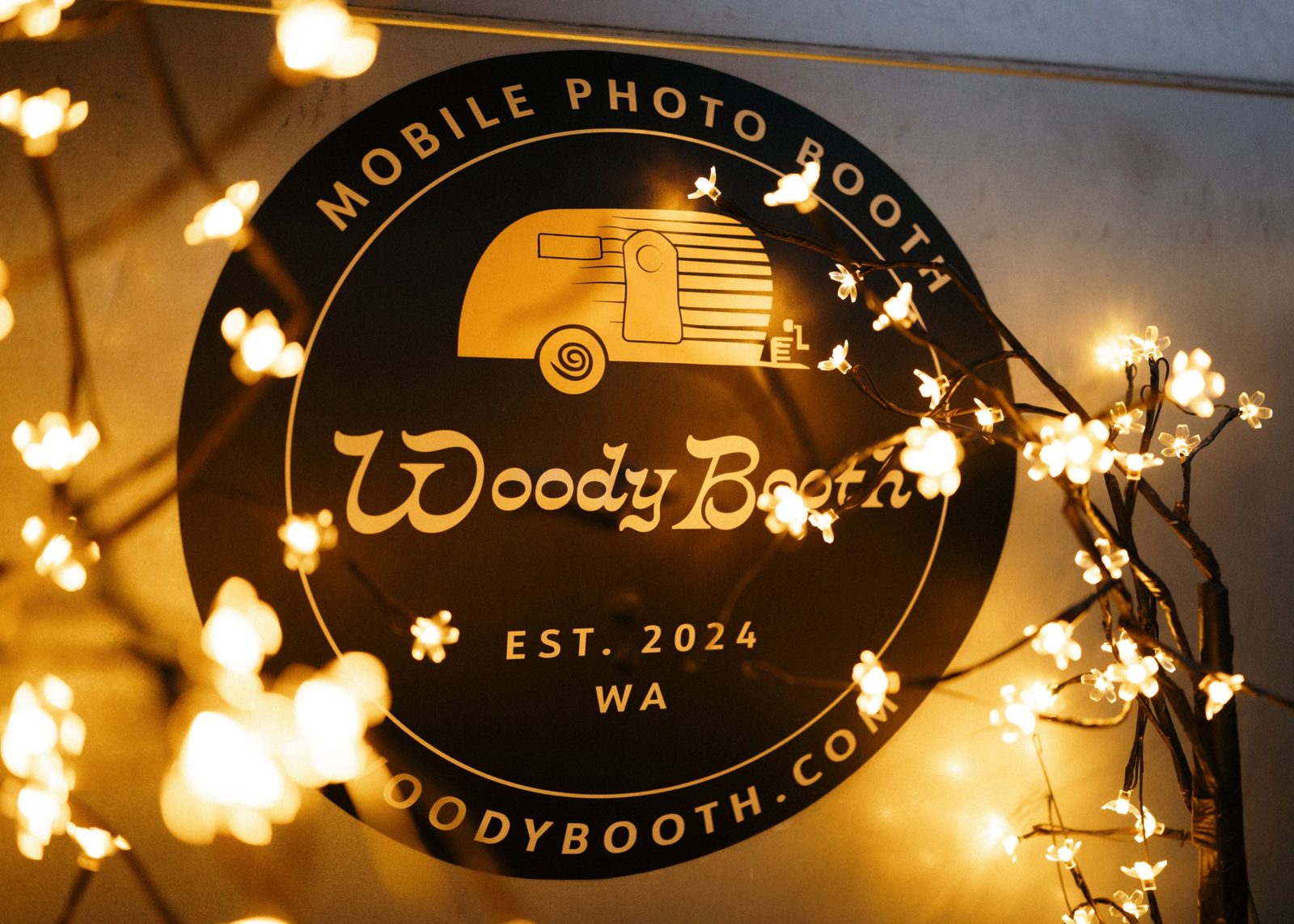 The Woody Booth logo sticker surrounded by string lights